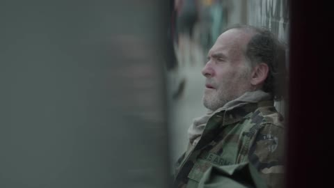 A homeless man sitting on the sidewalk in the city