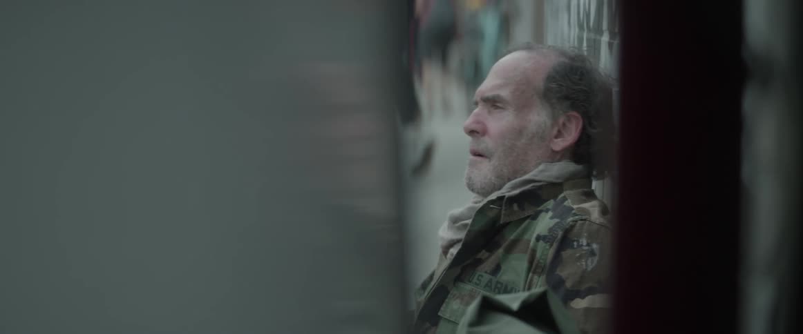 A homeless man sitting on the sidewalk in the city