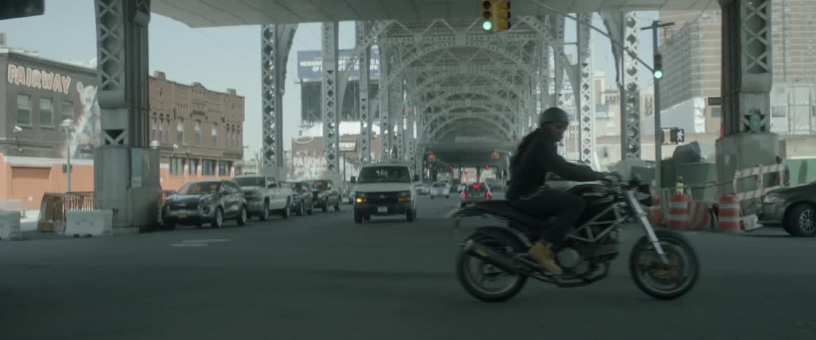 Cars drive under a bridge in a city