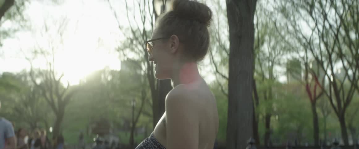 A woman in strapless top smiles in the park