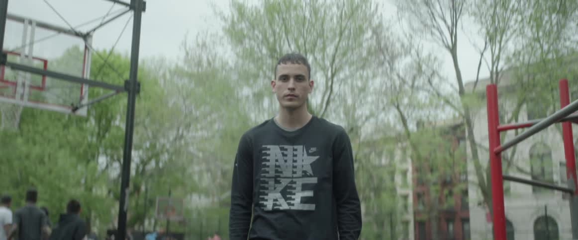 Young man stands still at a basketball court in the city