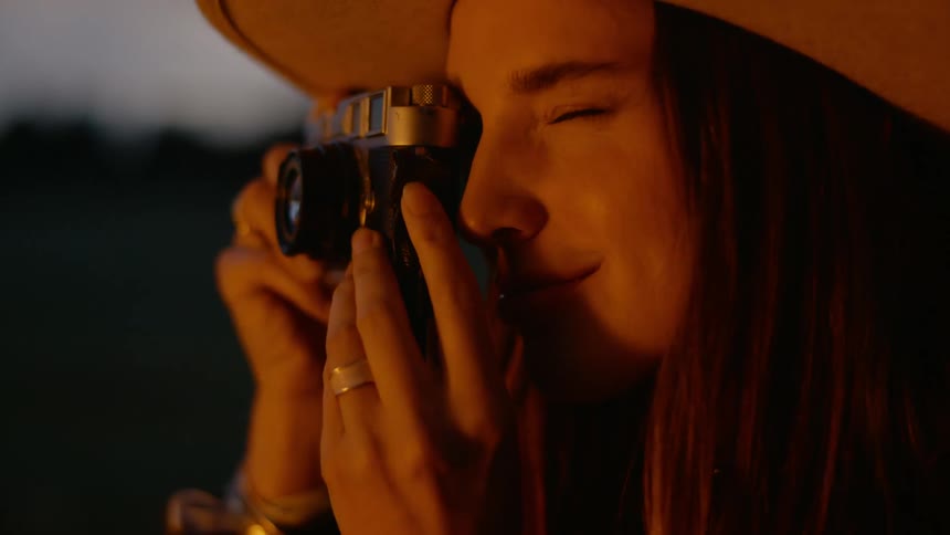 Portrait of a woman with a hat sitting and using a vintage camera