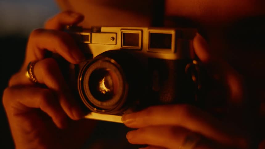 Firelight illuminates the face of woman taking pictures outdoors at night
