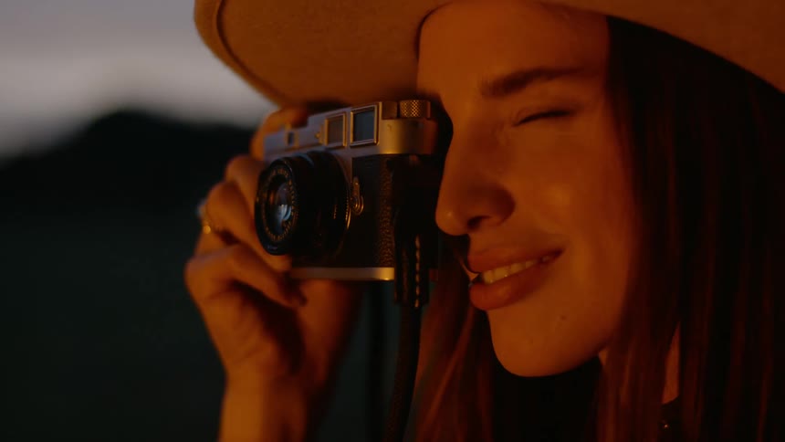 Smiling female photographer takes pictures near a campfire at night