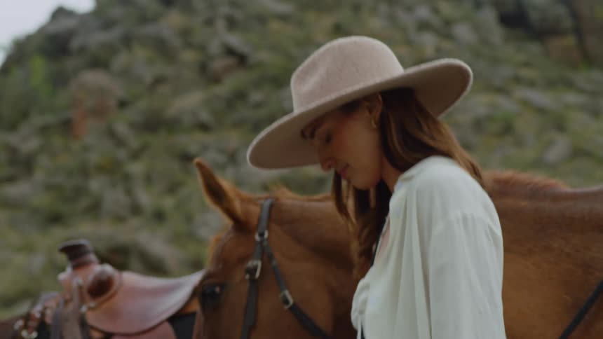 People lead their horses past a scrub covered hill