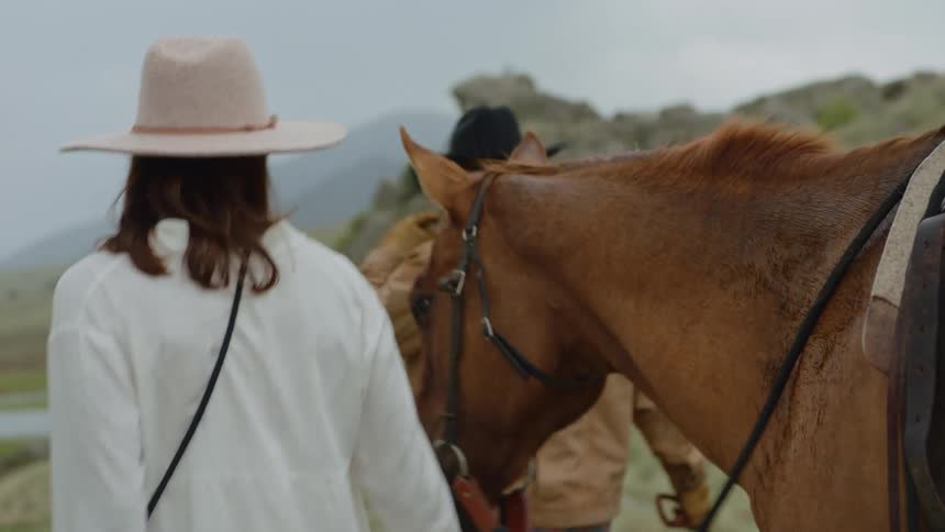 Man and woman walking and guiding horses through a mountain valley