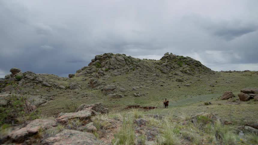Landscape of a mountain valley and two people riding horses