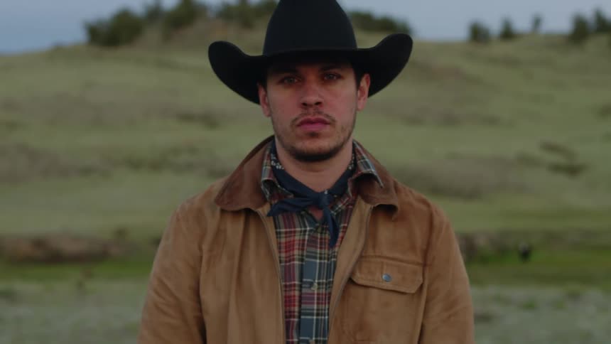 A mans face looking down and raising his head to stare straight ahead and he is wearing a talking hat