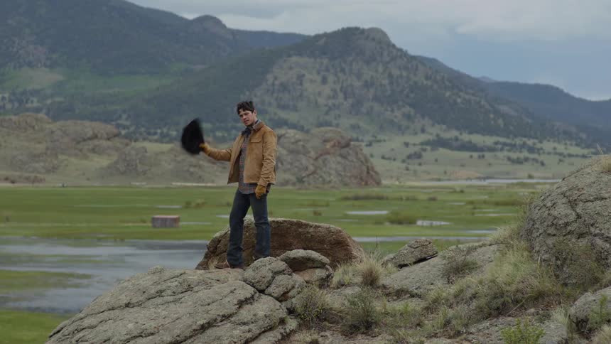 Man climbing a rock wearing a cowboy hat and then climbing down