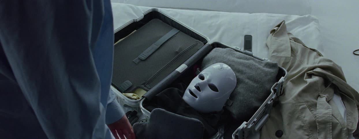 A person opens their luggage and removes a mask