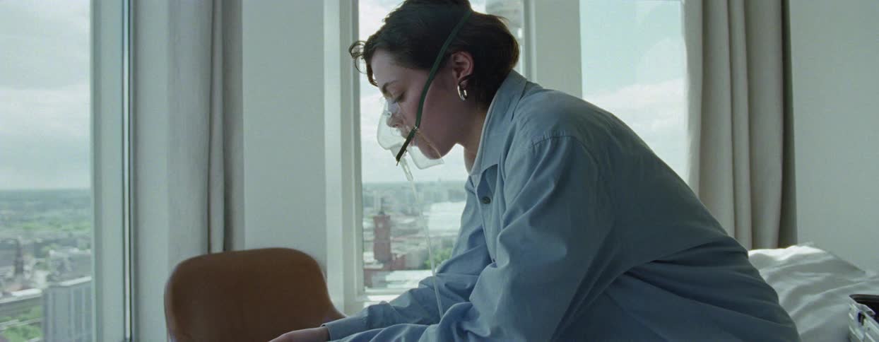 Woman indoors taking deep breaths with an oxygen mask