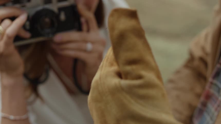 Woman with a vintage camera photographing an insect in a persons gloved hands
