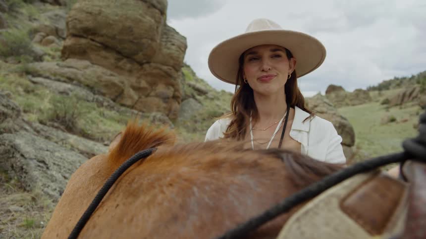 A woman takes a photo by her horse