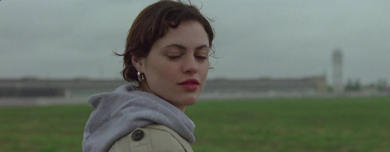 Portrait of a woman giving a smile while standing in a grass field on a cloudy day