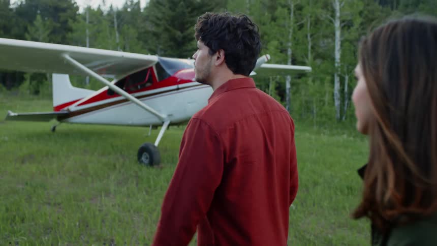 Man and woman walking in a field next to a small private plane