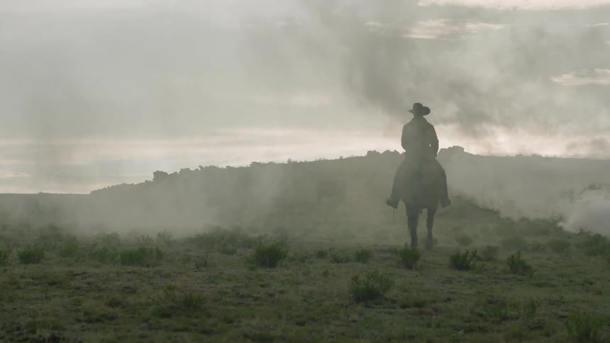 Man riding a horse in a natural environment with smoke and mountains in the background
