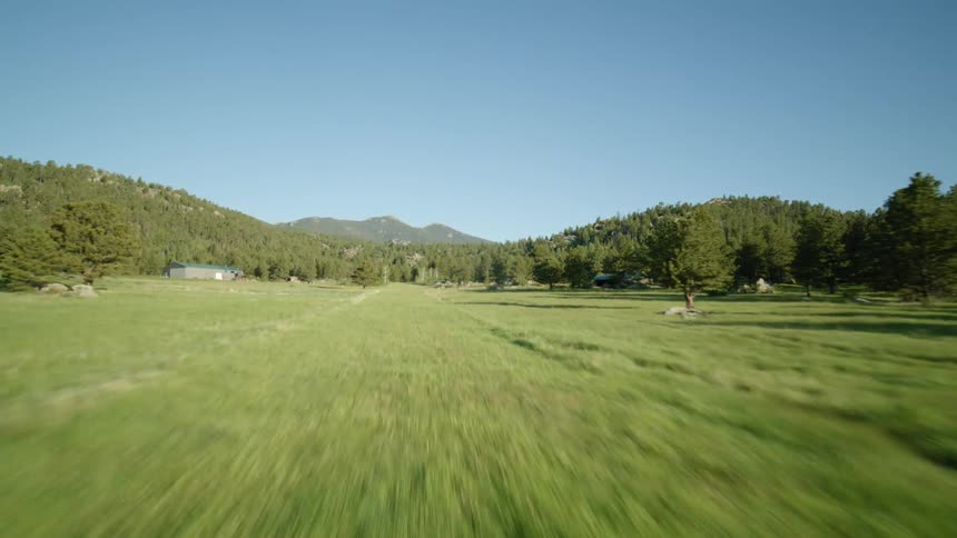 Small plane taking off over a green field with mountains in the background