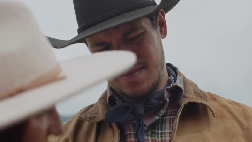 While standing in a field man holds a bug and talks to the female photographer taking pictures of it