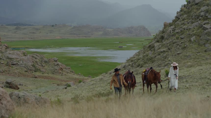 A man and woman walk their horse through the grass
