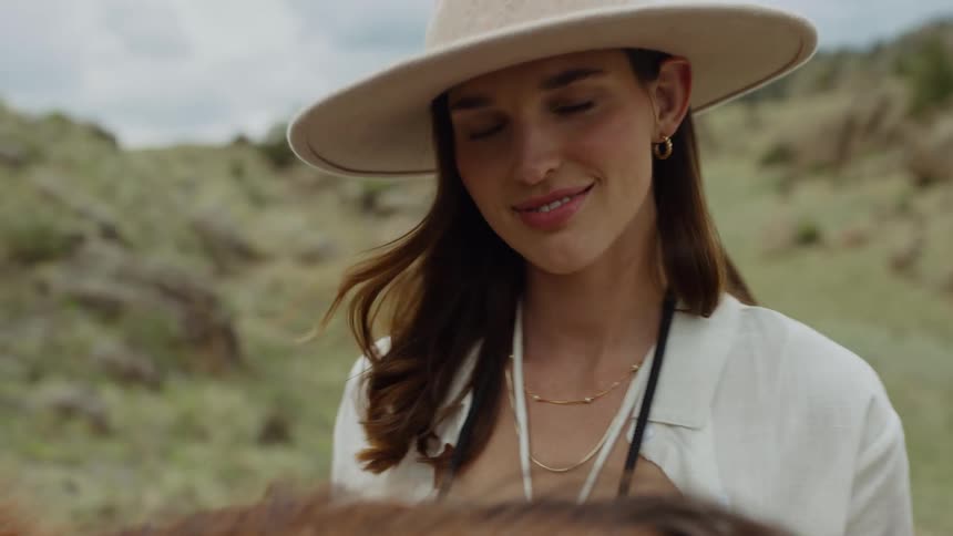 Woman in hat in natural setting using vintage camera next to a horse
