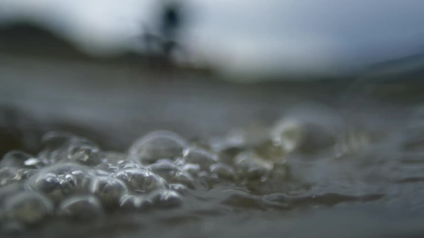 The surface of a clear liquid moving and making some bubbles
