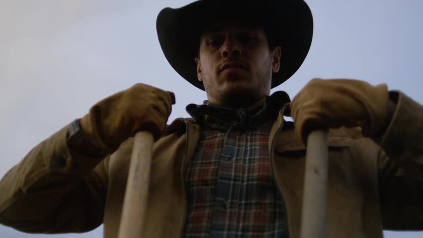 Cowboy holding two thin wooden stakes