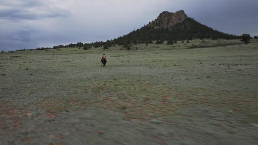 Man riding a horse in a mountain valley on a cloudy day
