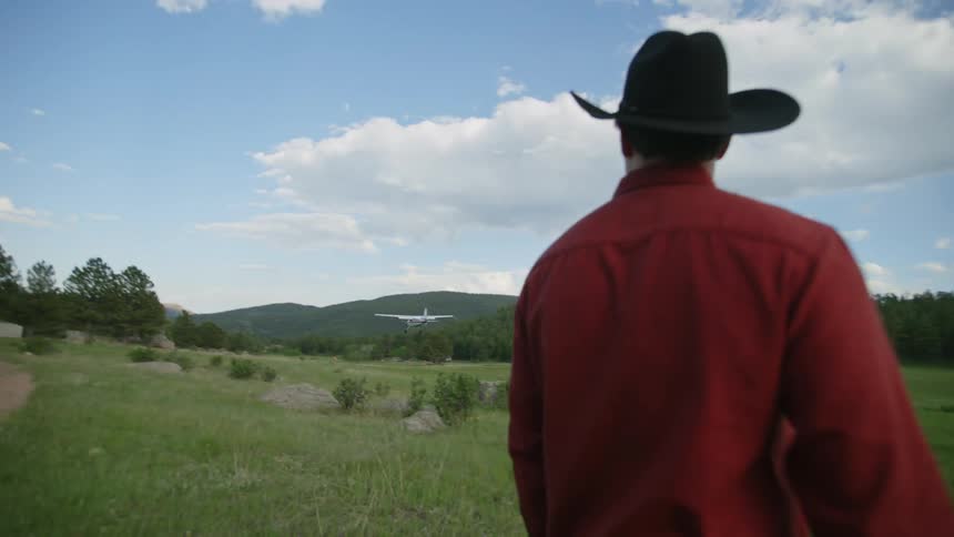 A man watches the plane fly over the field