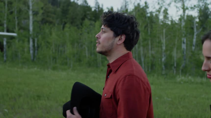Man and woman walking in a field with a single engine plane next to them