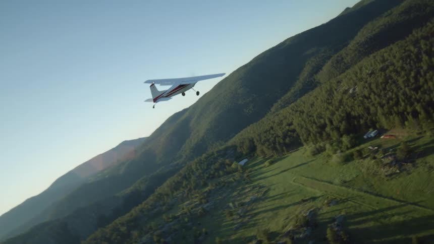 Small plane flies over a highway passing farms in the forested countryside