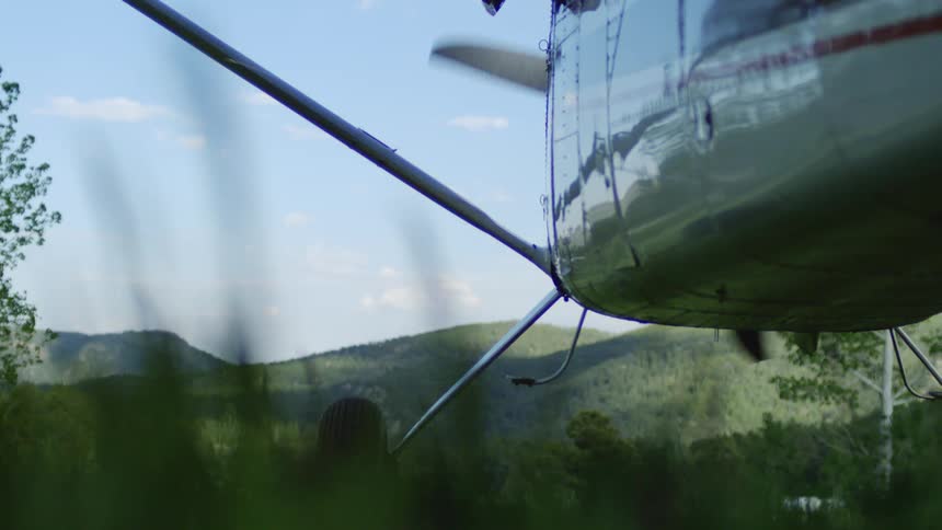 Propeller of an airplane in motion while stationary in a field with mountains on the horizon