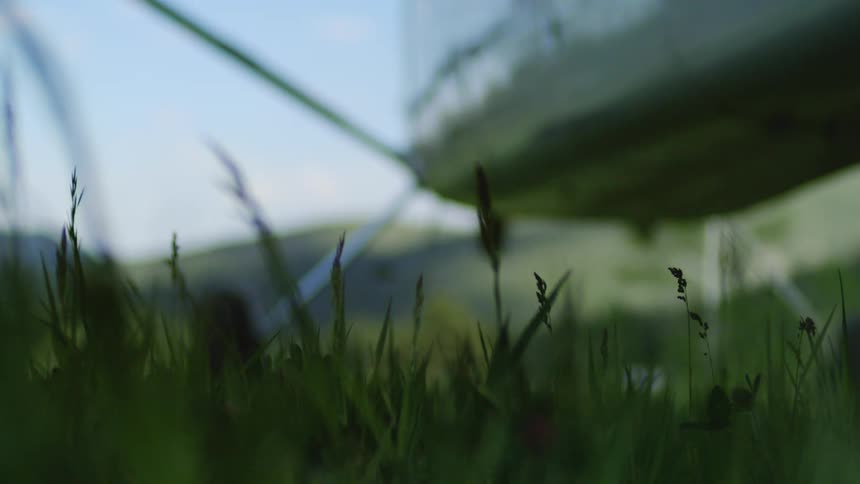 Single engine airplane with propeller spinning while landing in a grass field