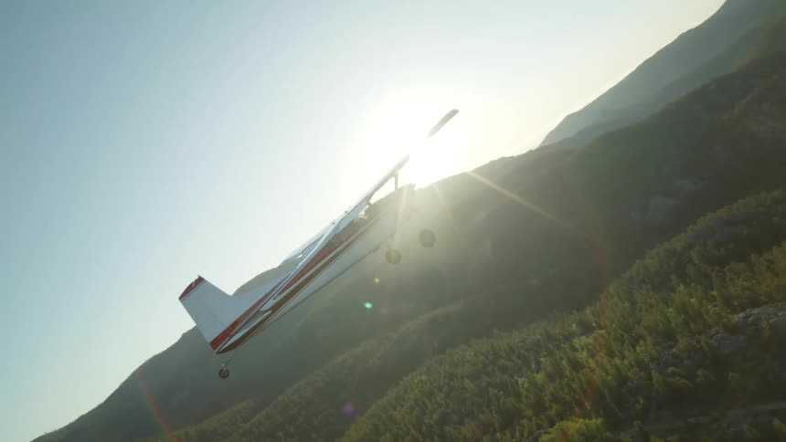 A small plane flying over lush green mountain hills and ridges
