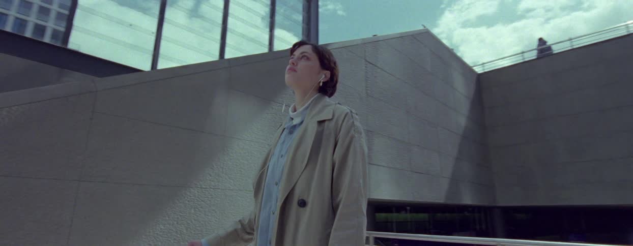 Woman with a long coat and a suitcase traveling through the city