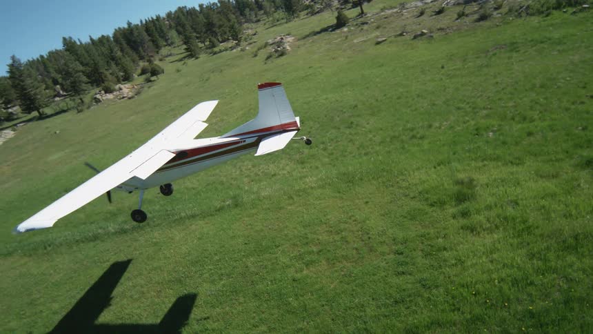Small plane flying low in landing motion over a green field