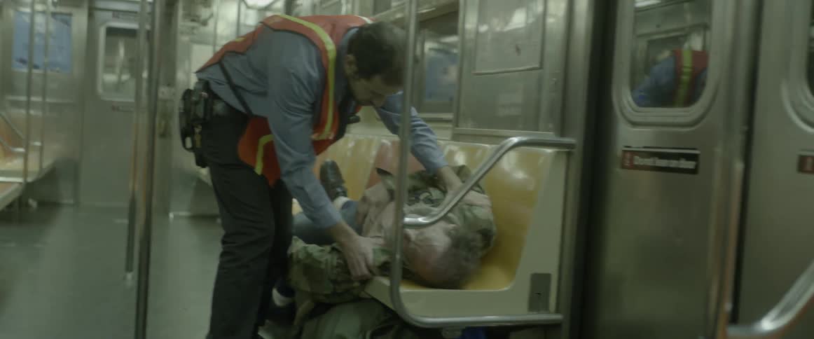 A man waking up a homeless person on a train
