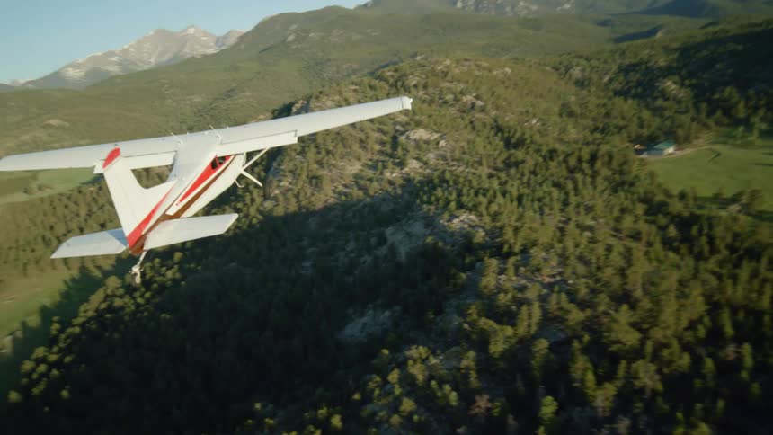 Aerial view of a small jet soaring in the sky above a heavily wooded area