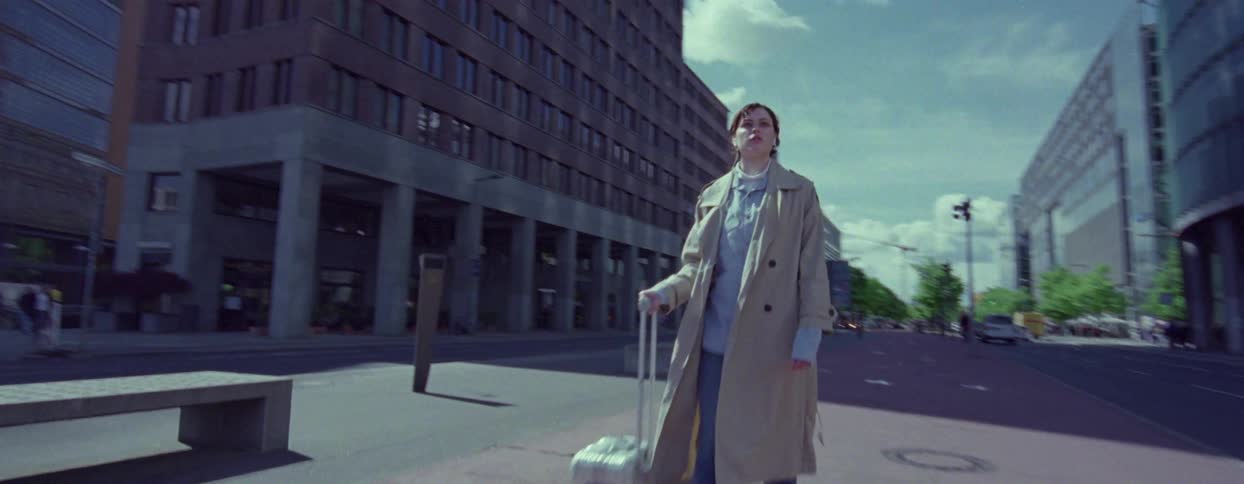 A woman rolls baggage down a city street