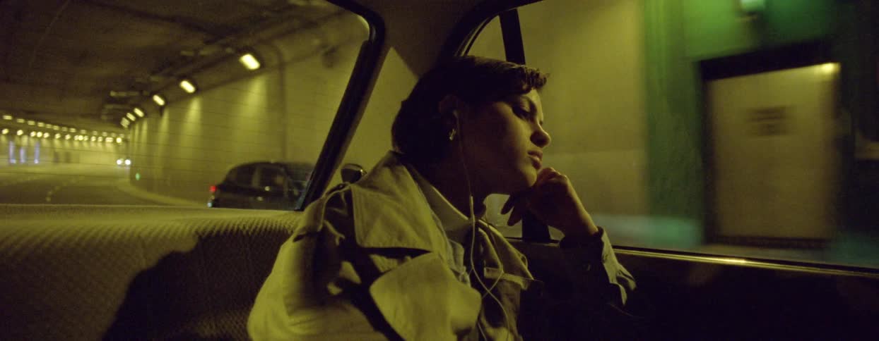 A woman is riding in the back of the car driving in the tunnel