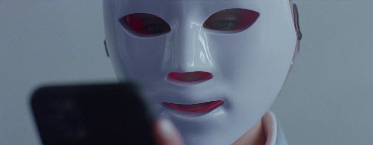 Portrait of a person wearing a mask and using a cell phone