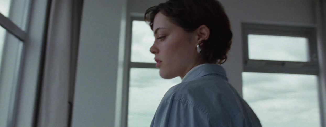 A woman enters the bedroom and looks out the window