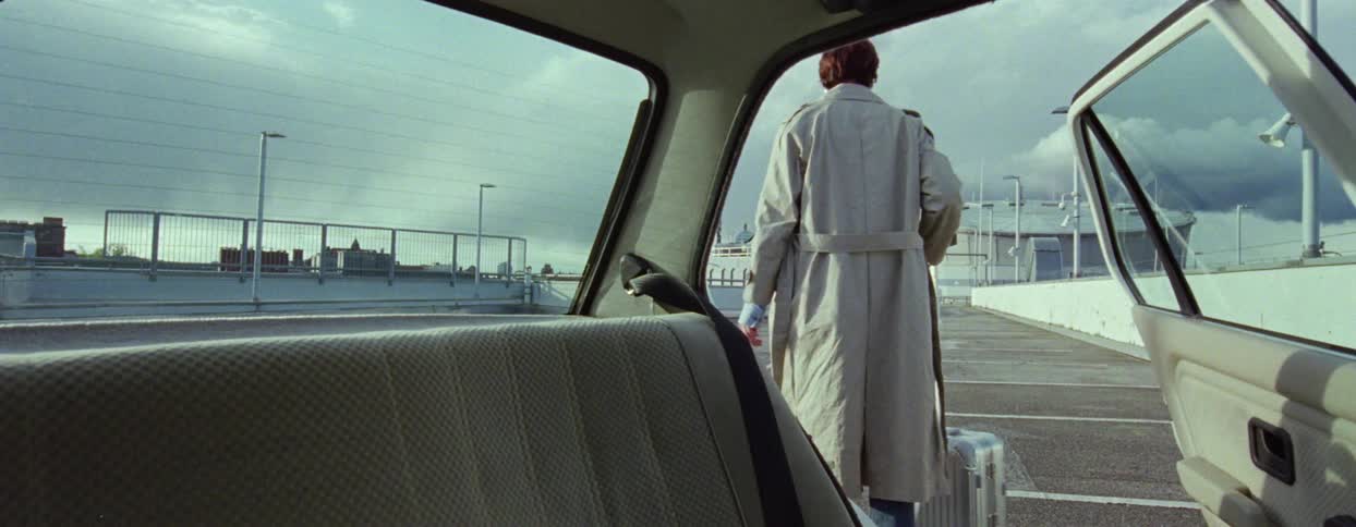 Woman getting out of a car with a suitcase and walking