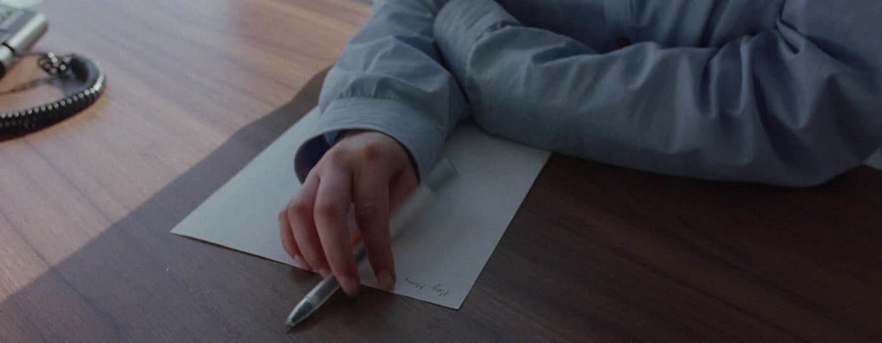 Office worker sitting at a desk in the city contemplates what to write on paper