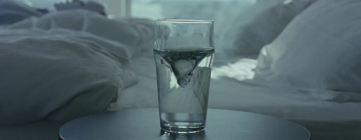 Glass cup next to the bed with water spiraling in motion