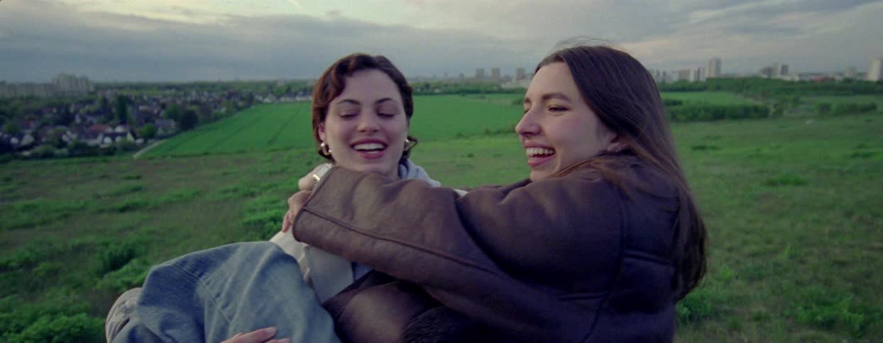 Girl jumping on the lap of a woman standing in a field