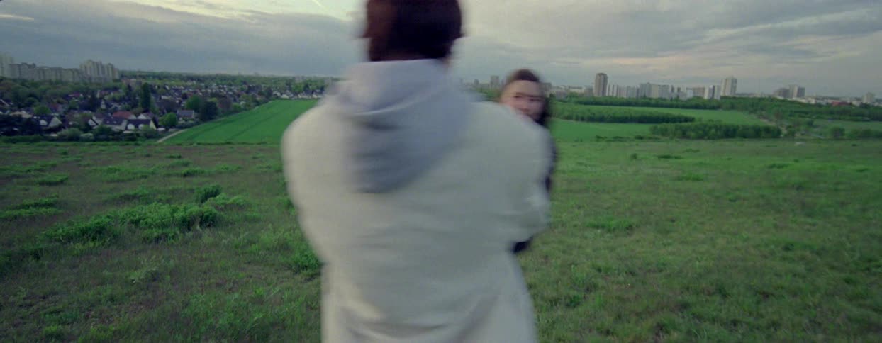 Two young women holding hands spinning and falling in a field