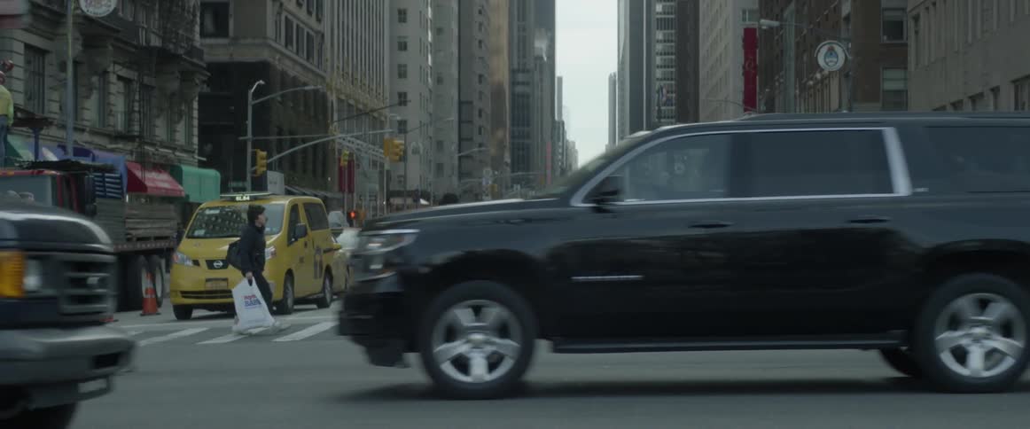 Pedestrians walk through a crosswalk in a busy city