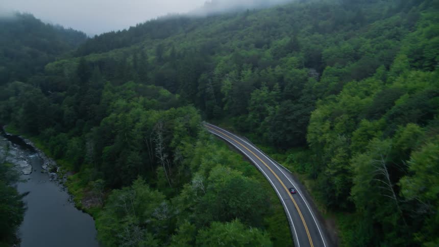 A car drives along a rural highway road next to a river