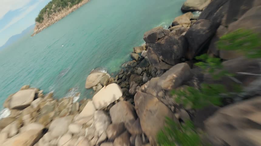 Paradise Island with a Shore Covered in Boulders Captured from a Low FPV Drone Perspective