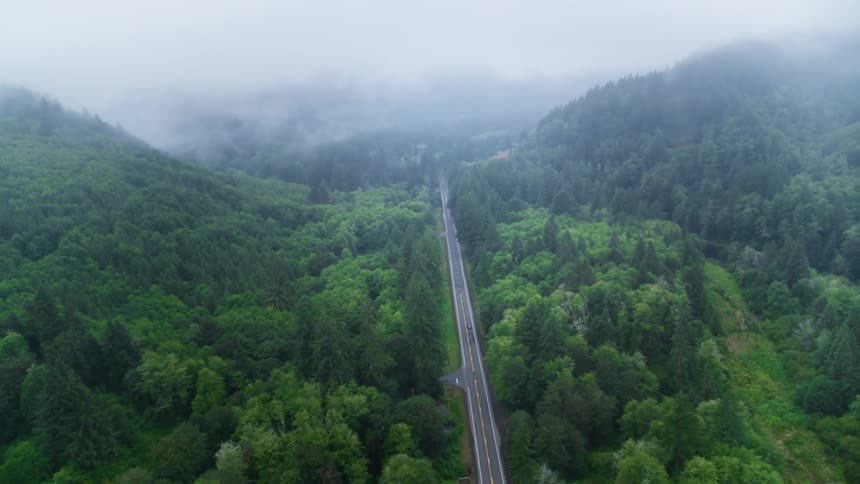 A car drives down a remote highway situated in a mountain valley